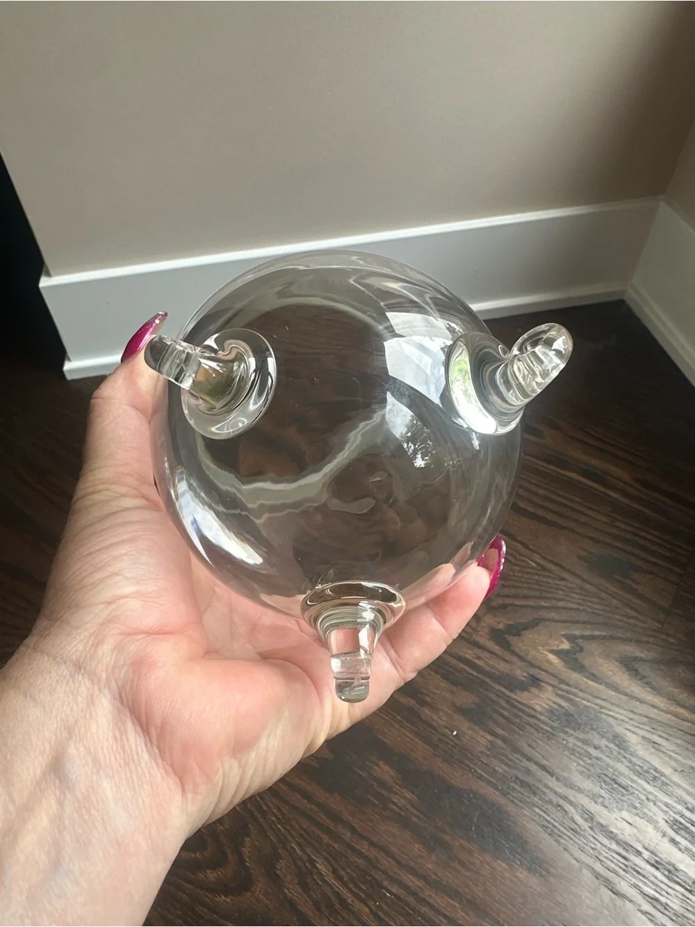Clear glass vase featuring a wide mouth and is elevated on three small legs